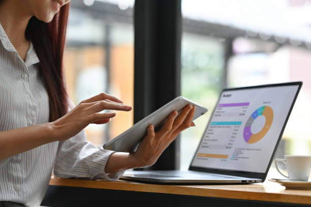 Close up of Businesswoman analyzing income charts and graphs with modern laptop and tablet. Business analysis and strategy concept.